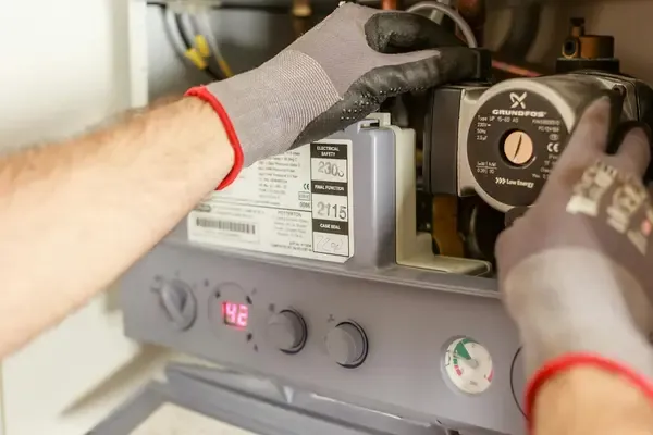 Hände am Heizsystem im Keller