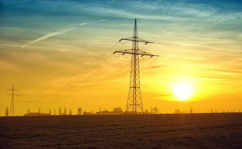 Freileitungsmast auf einem Feld vor bewölktem Himmel